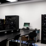 Laboratório contemporâneo de eletrônica com bancadas, computadores e equipamentos técnicos para pesquisa.