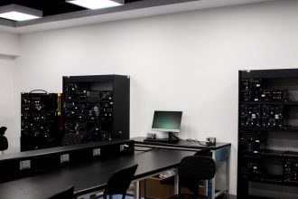 Laboratório contemporâneo de eletrônica com bancadas, computadores e equipamentos técnicos para pesquisa.