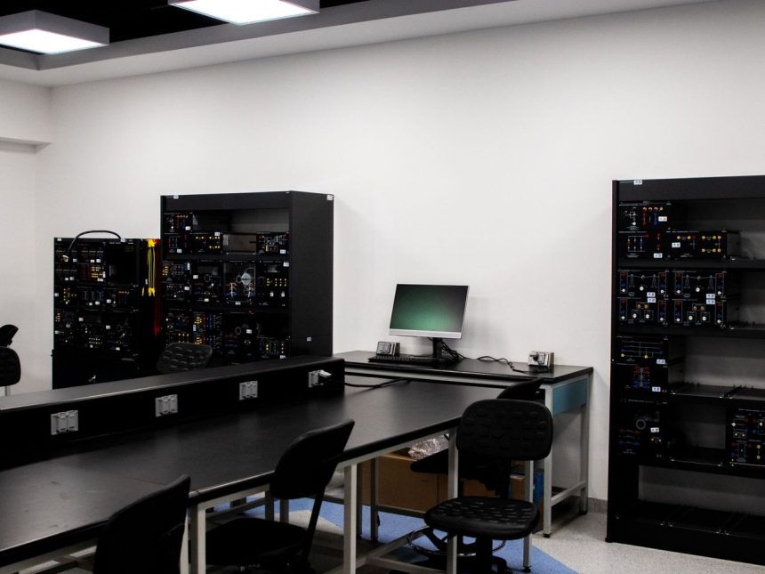 Laboratório contemporâneo de eletrônica com bancadas, computadores e equipamentos técnicos para pesquisa.