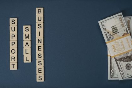 Composição conceitual com dinheiro e peças com letras representando apoio financeiro a pequenos negócios.