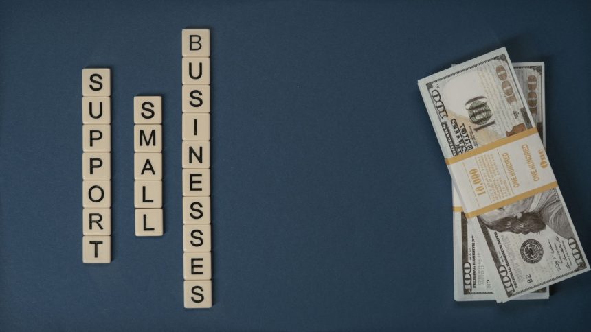 Composição conceitual com dinheiro e peças com letras representando apoio financeiro a pequenos negócios.