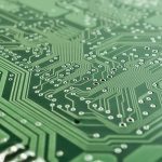Close-up de uma placa eletrônica com circuitos, chip e componentes de processamento.