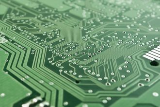 Close-up de uma placa eletrônica com circuitos, chip e componentes de processamento.