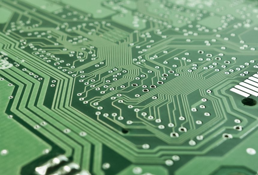 Close-up de uma placa eletrônica com circuitos, chip e componentes de processamento.